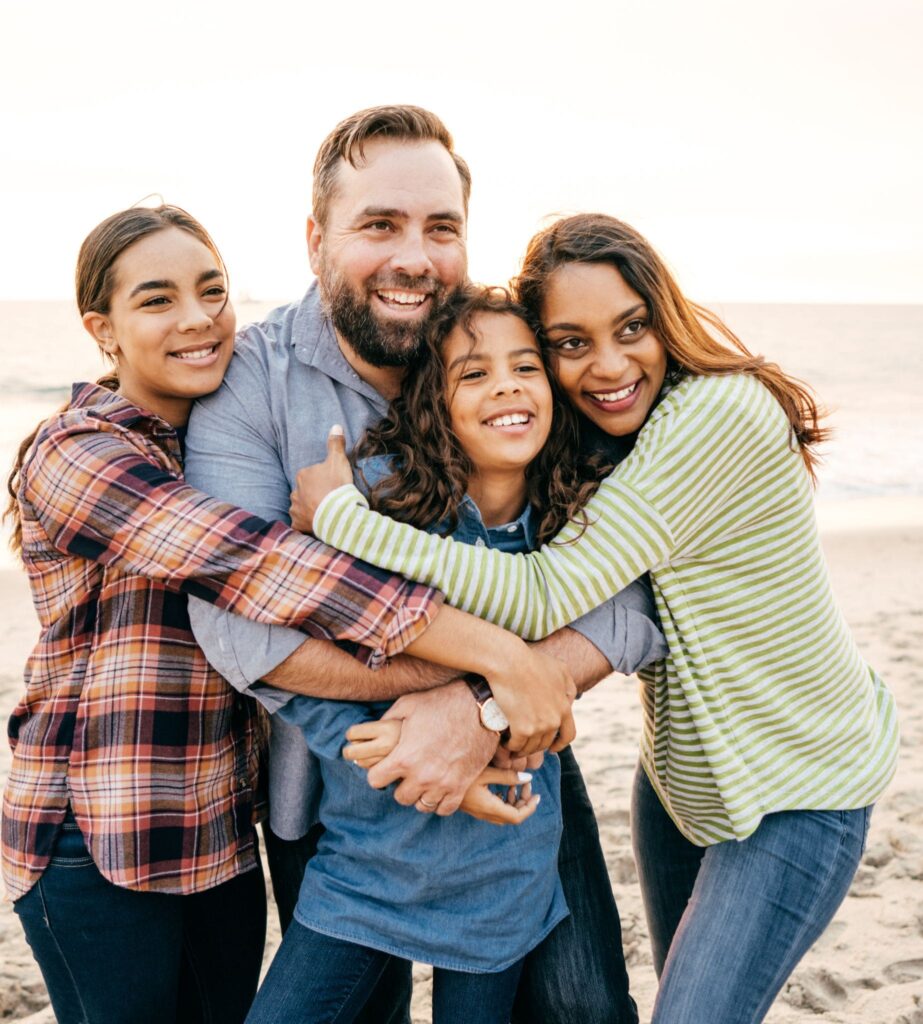 Angela Evans Holistic Life and Family Coach. Family picture, 2 teenage girls a mum and dad on a beach smiling.